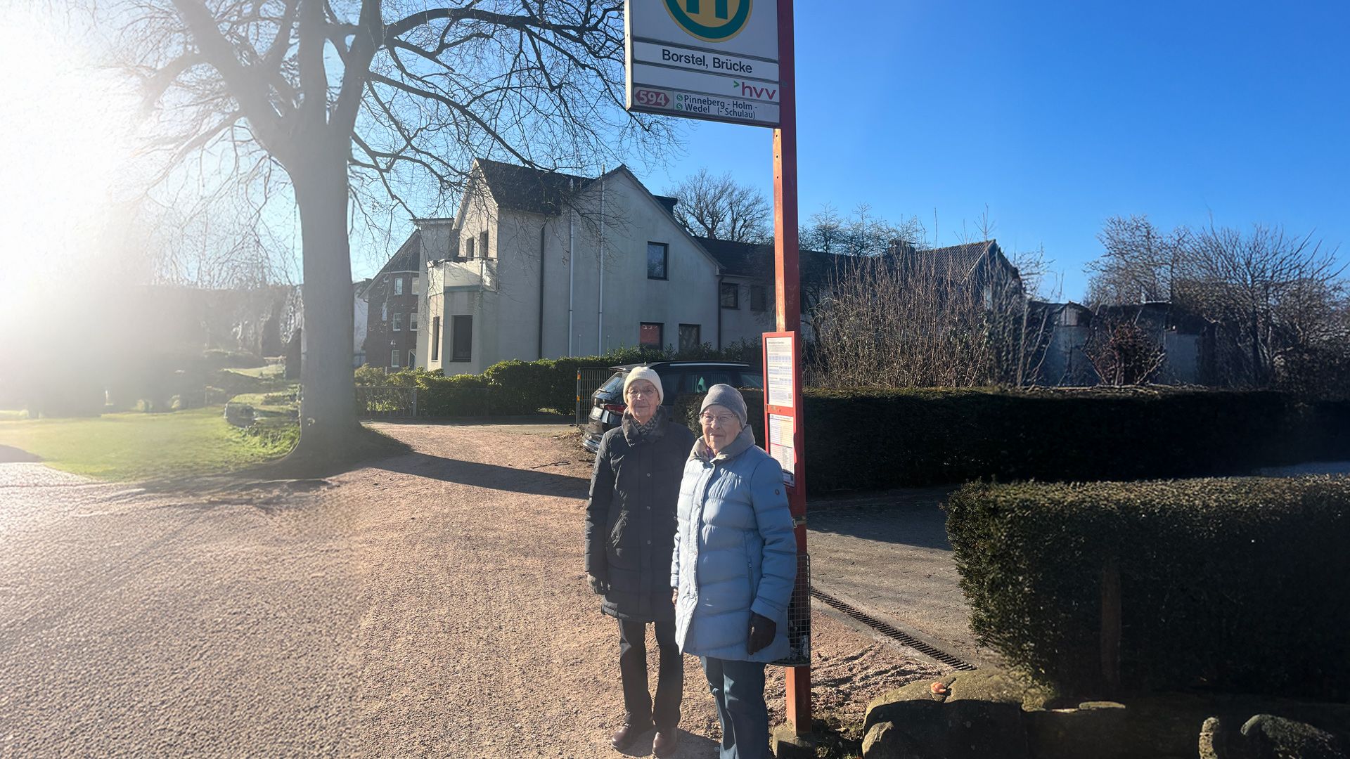 Zwei Personen an einer Bushaltestelle