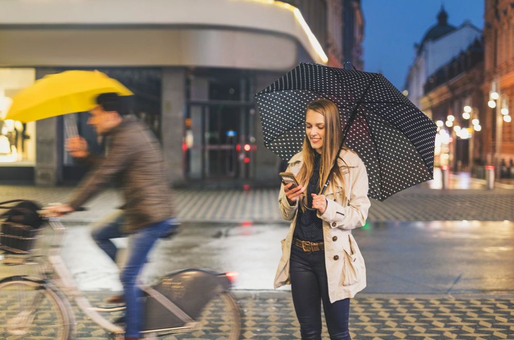 Junge Frau steht in der Innenstadt und schaut in ihr Smartphone
